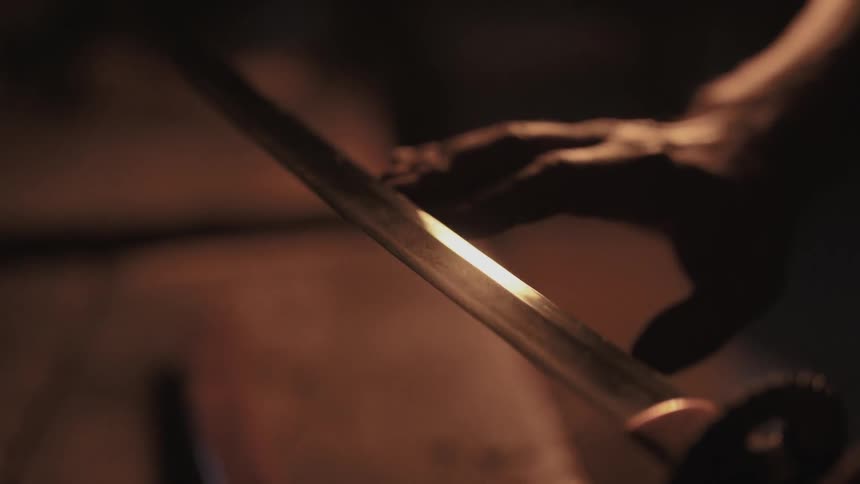 A person traces his hand along a sword