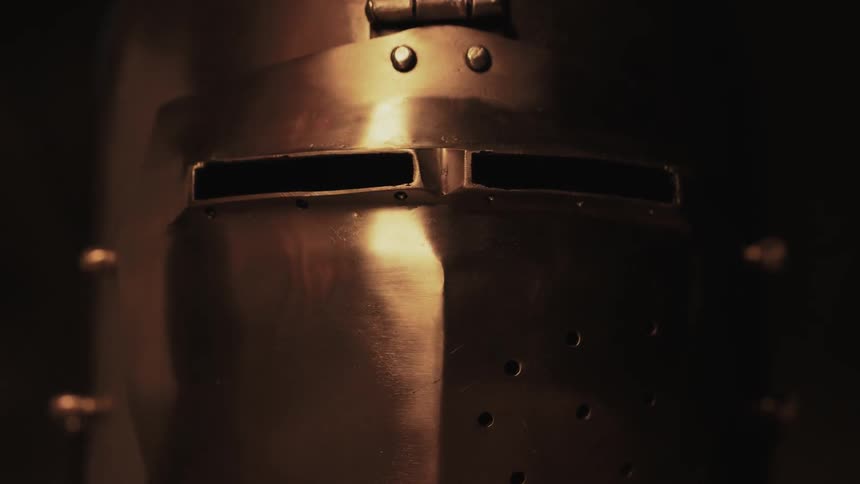 Light sweeping across the face mask of a metal helmet