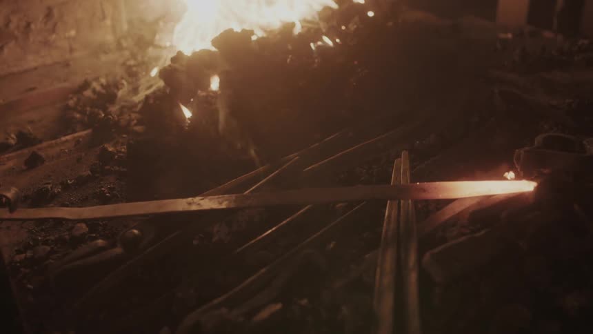 A blacksmith setting a project down next to a fire