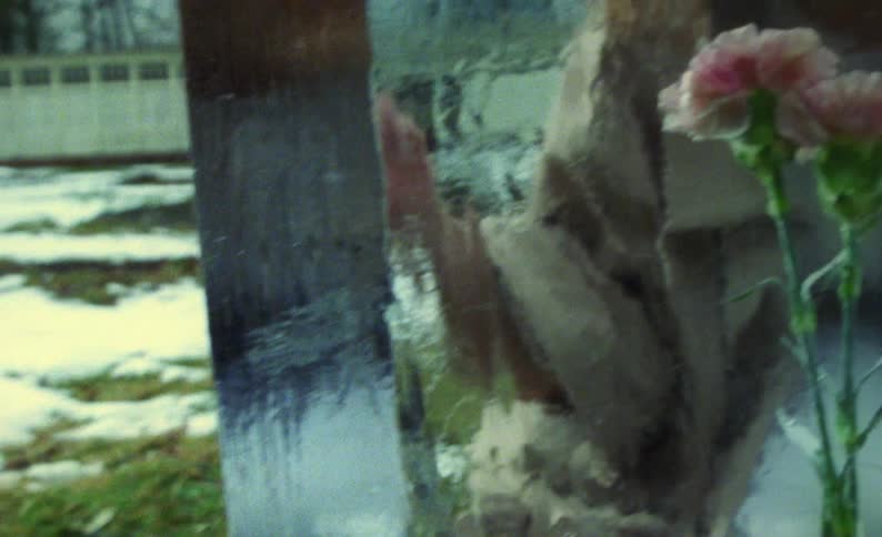 A woman picks up a chisel after looking at fresh flowers frozen in a large block of ice