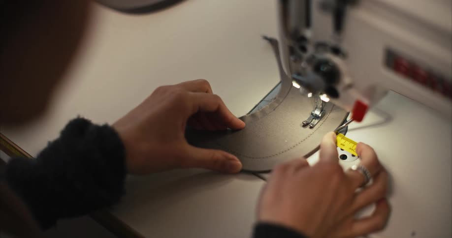 A woman uses her fingers to guide a curved piece of fabric through the sewing machine