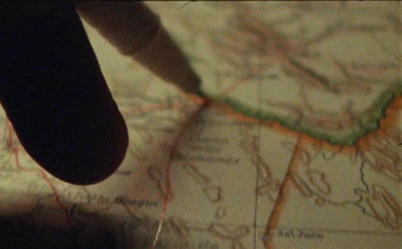 A hand holding a pen draws a red line on a map
