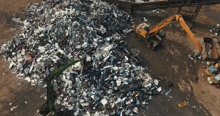 Dump trucks pick up garbage and put it in a pile at a dump