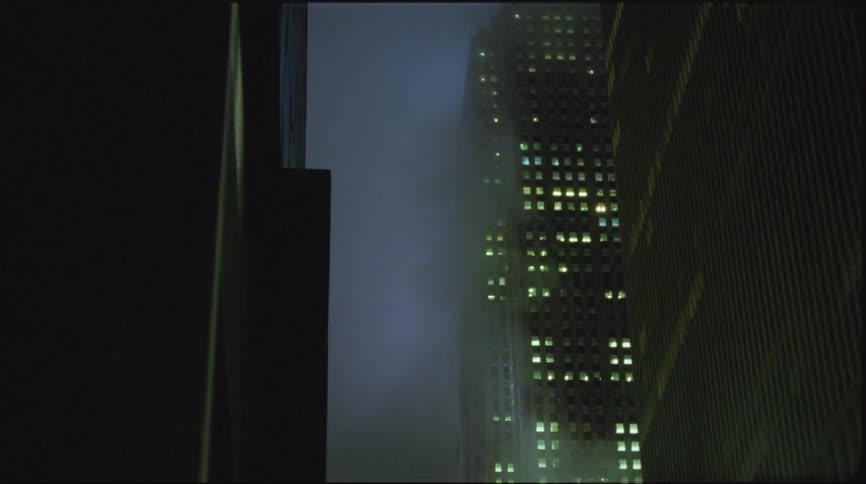 Illuminated high rise buildings seen from foggy street in city
