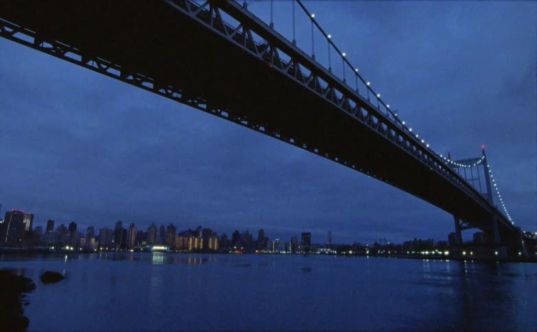 Camera shows view of a bridge going toward a distant city on a cloudy morningevening