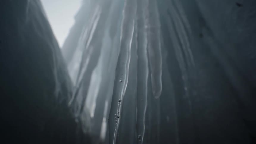 Water droplets slide down melting icicles, close up