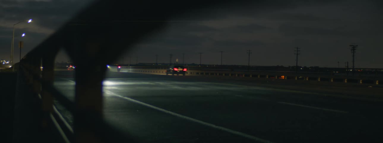 Cars and trucks speed by on a freeway at night