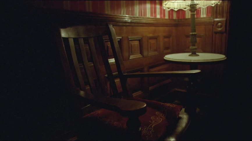 Wood armchair with red cushion next to lamp and wainscoting