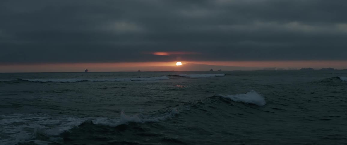 Large ocean waves wash onto the beach at sun set