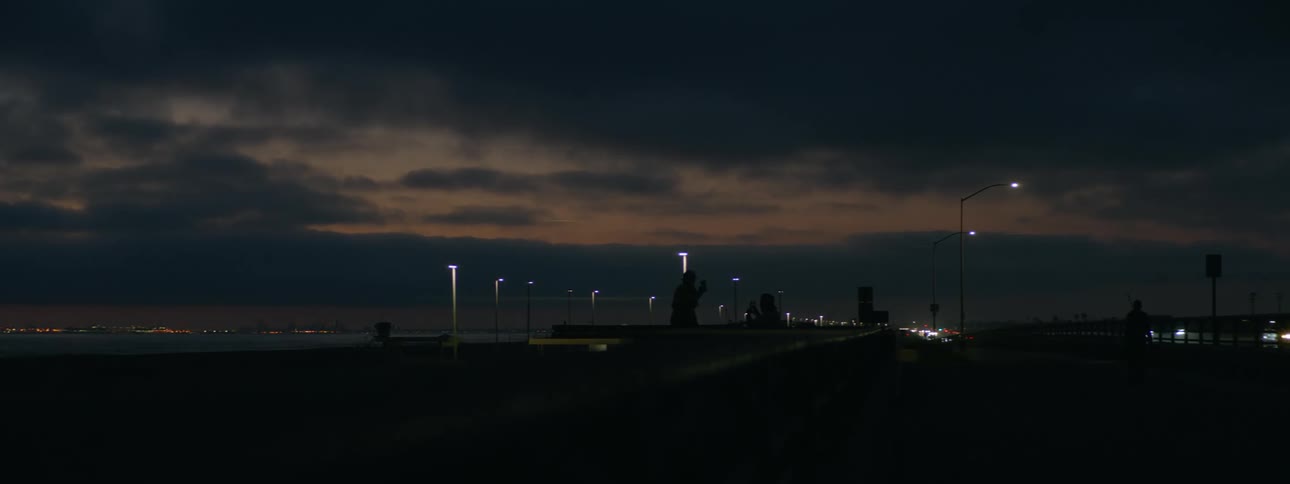 The headlights of automobiles shine in the darkness as traffic moves on a highway at night