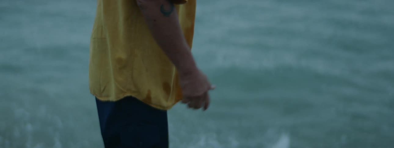 A man holding a fish before throwing it back into the ocean with a splash
