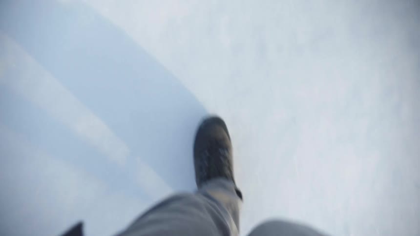A man walks slowly on snow covered ground