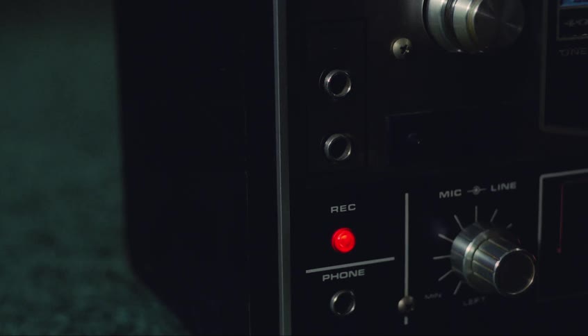 A man turns a dial on a vintage recording device
