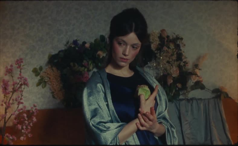 A woman poses holding a flower