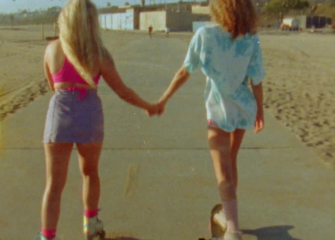 Two women hold hands and skate together
