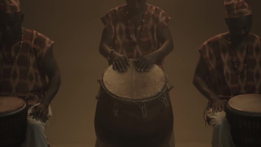 Three men are leaning over large drums
