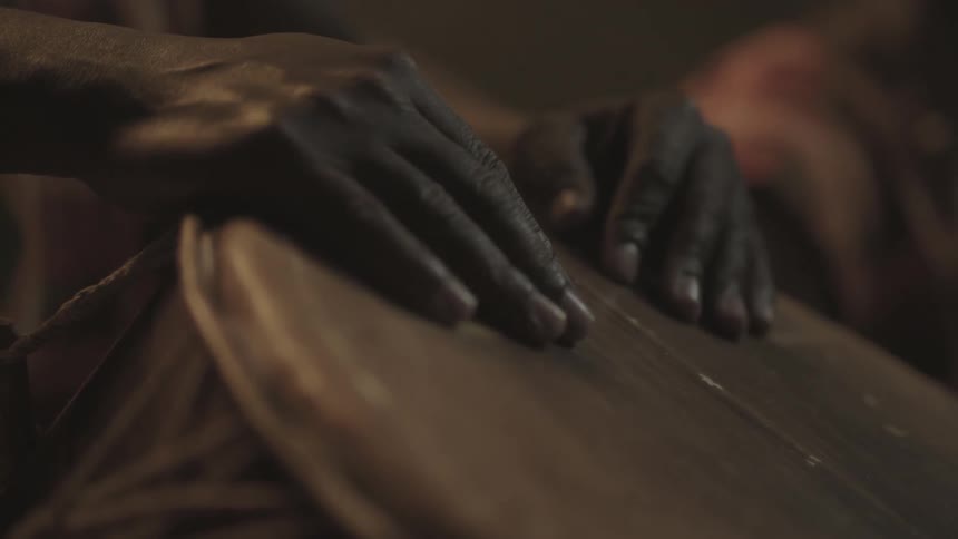 A person has their hands laying on a drum