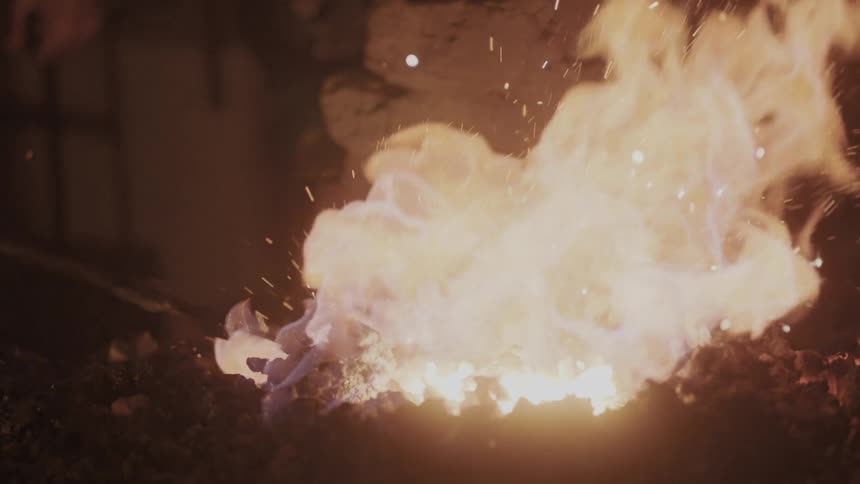 A fire gives off sparks in a dark room