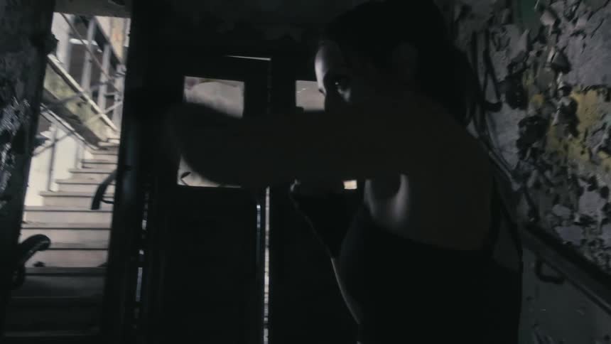 Female boxer trains in room of abandoned building with peeling paint