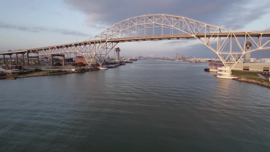 Cars driving across a bridge over a lake with a city skyline in the distance