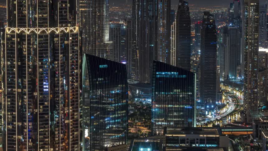 Traffic moves along a street in a large city full of many skyscrapers