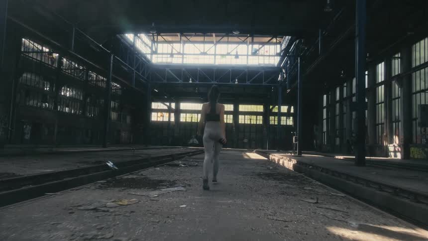 A woman walks through the abandoned warehouse