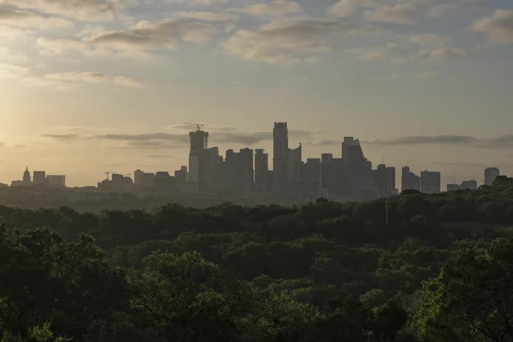Clouds move over a city overlooking a forest