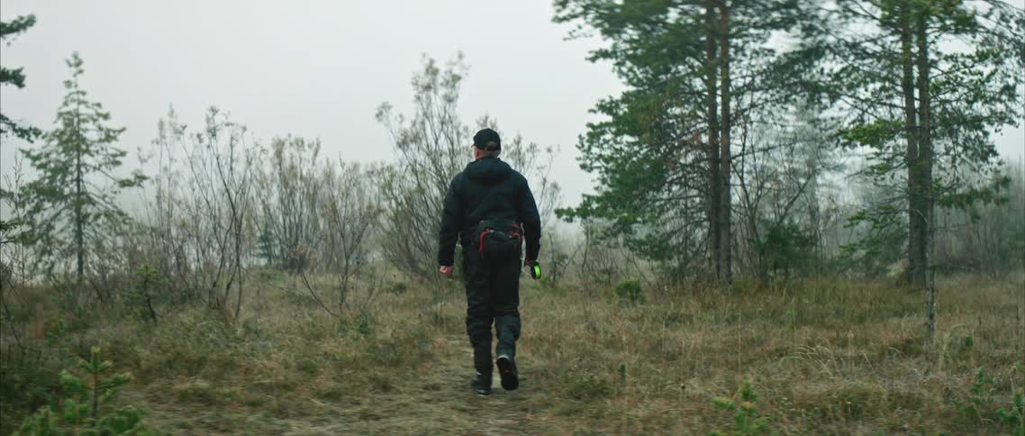 Man hikes on a trail on the wilderness next to a forest covered in mist