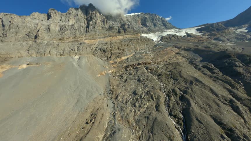 A mountain range with some snow and clouds above it