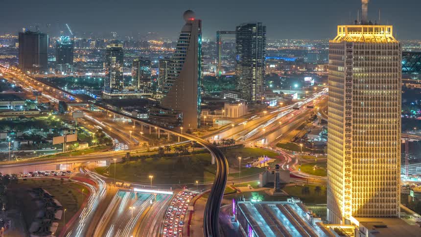 Aerial view of illuminated high rise buildings and traffic on the roundabout in the city