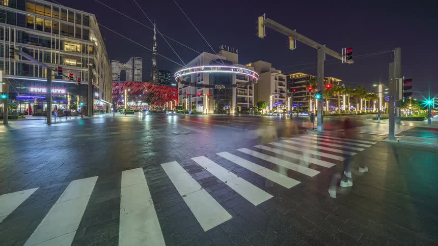 Busy city intersection with pedestrians and illuminated buildings in the city