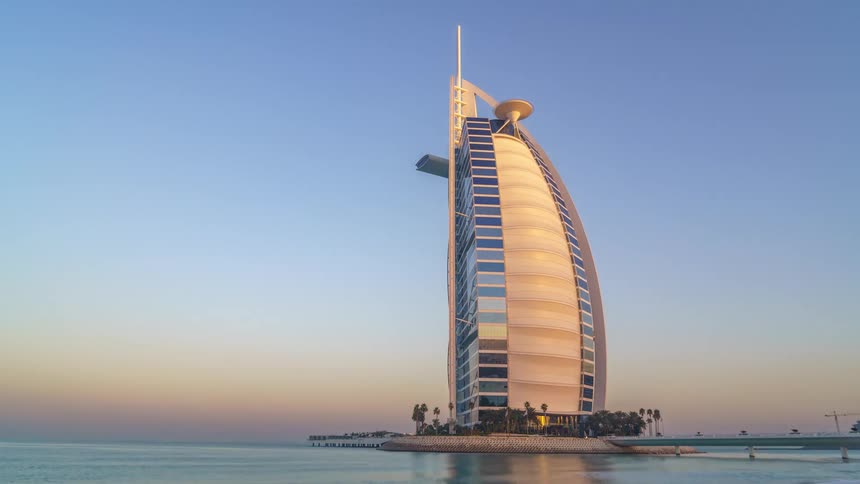 Exterior view of burj al arab tall hotel standing on artificial island