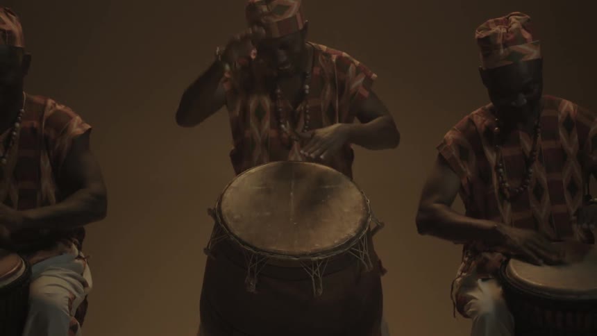 Tribesmen beat drums during a performance