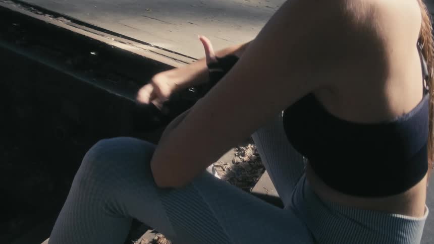 Woman sits at top of steps wrapping her hands for exercising