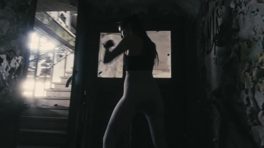 A woman is boxing in a building near a door