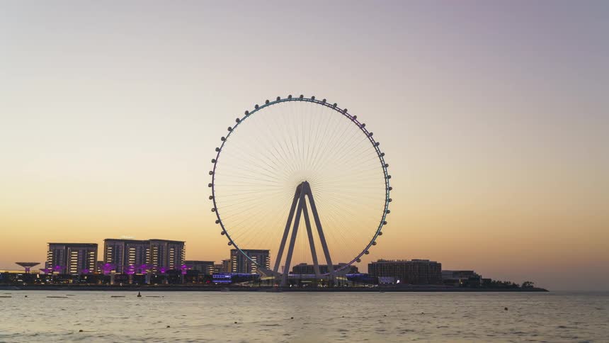 Time lapse of a ferris wheel spinning in front of a city skyline next to the ocean