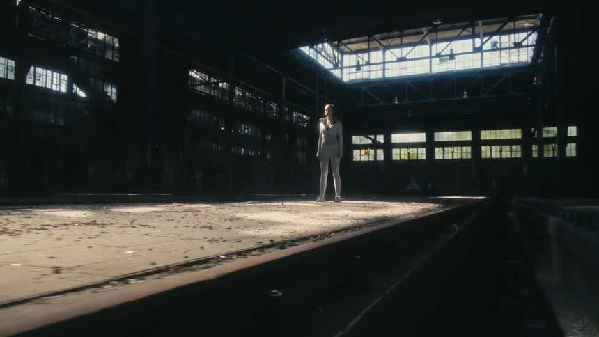 A woman in a white uniform is standing on a dirty platform in a building