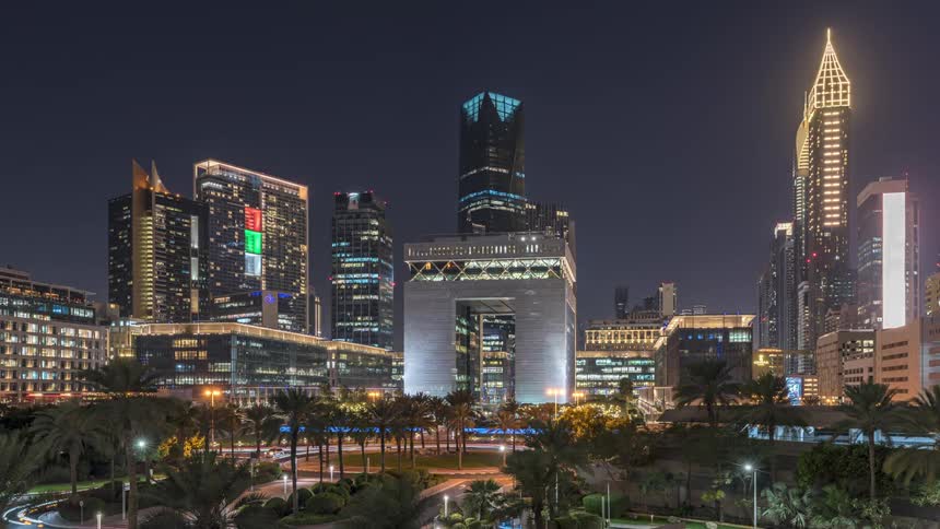 Traffic moves along a road in a city with tall buildings