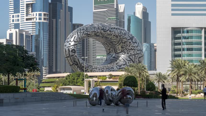 People stop near sculptures in a city plaza