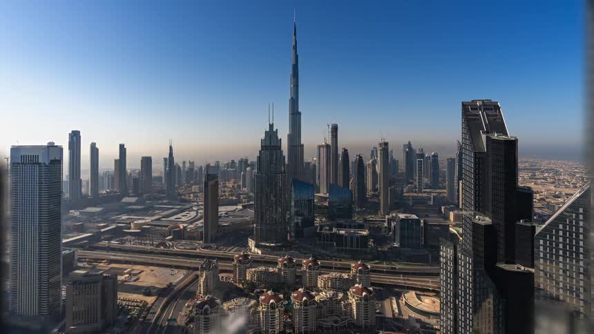 Aerial view of large city with high rise buildings skyscrapers vehicles driving on highways during the day