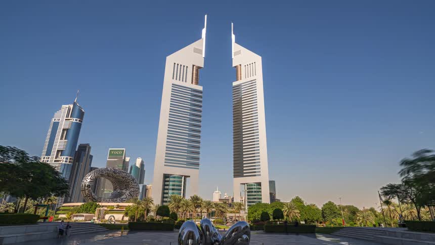 Traffic and pedestrians move on the roads near tall towers and futuristic buildings in the city of dubai