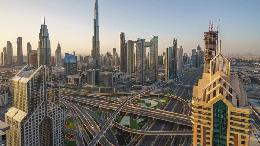 Traffic moves on the winding freeway below tall towers and futuristic buildings in the city of dubai