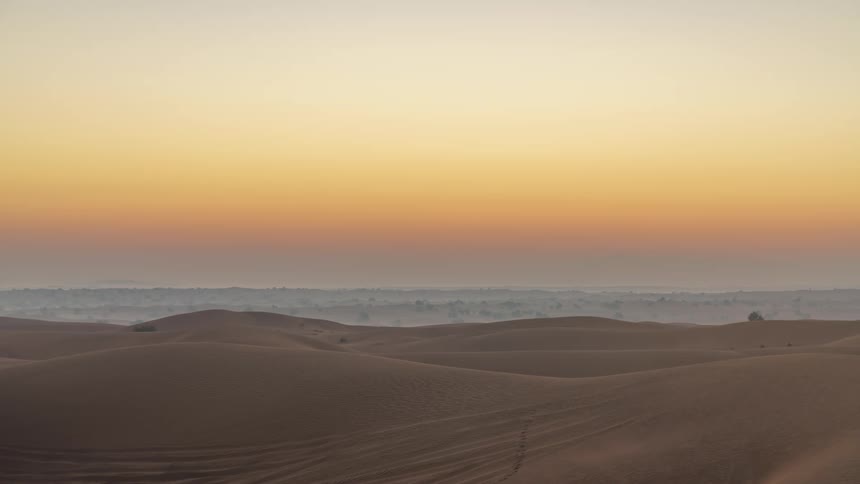 Time lapse of the sun rising ona red sky over the sand dunes in the desert