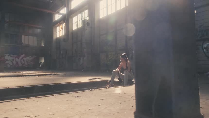 Woman with ponytail black sports bra and gray yoga pants ties hand wraps in building