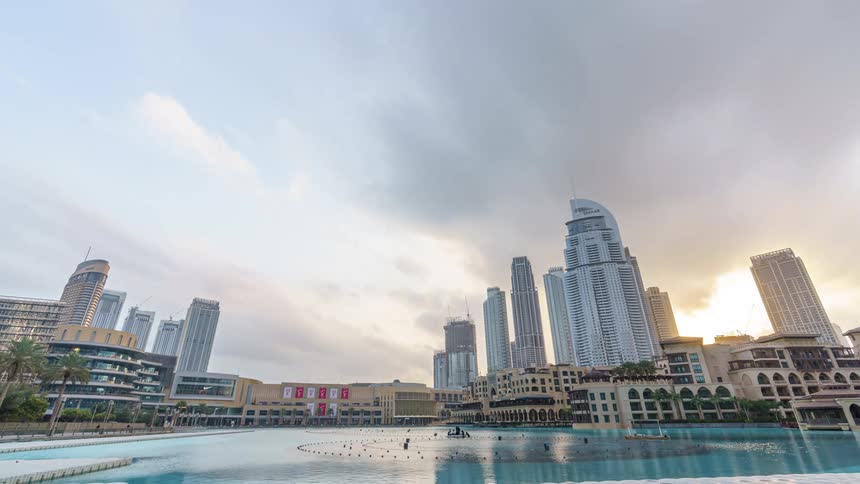A time lapse of people boating in a water way in front of skyscrapers