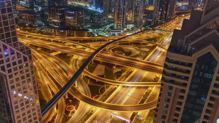 Traffic moves along complex network of highways in middle of downtown at night and during the morning