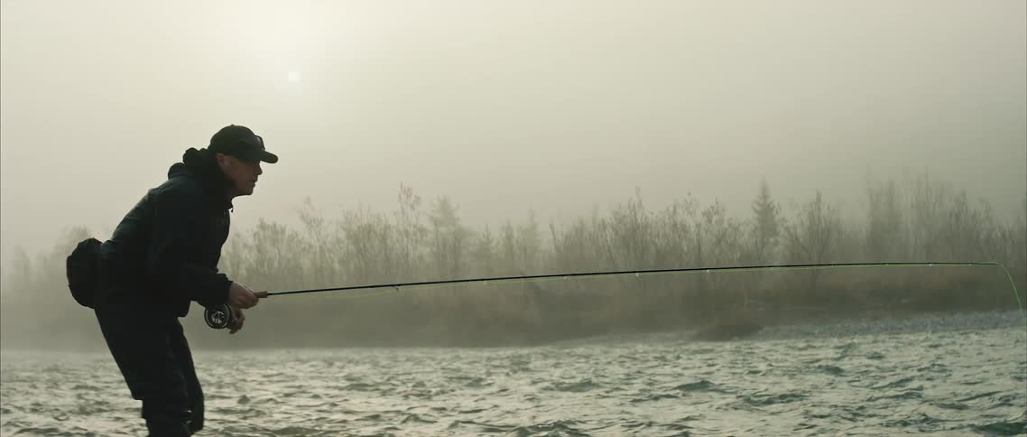 A man is fishing on a body of water during the daytime