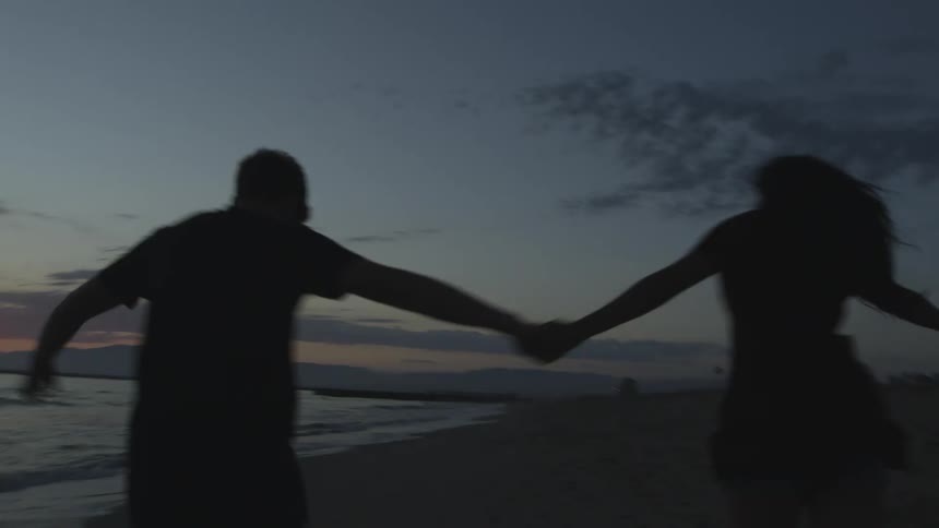 Man and woman are running on the beach together