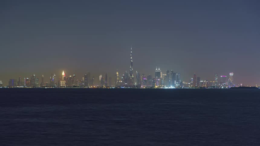 A boat sails through the ocean past downtown