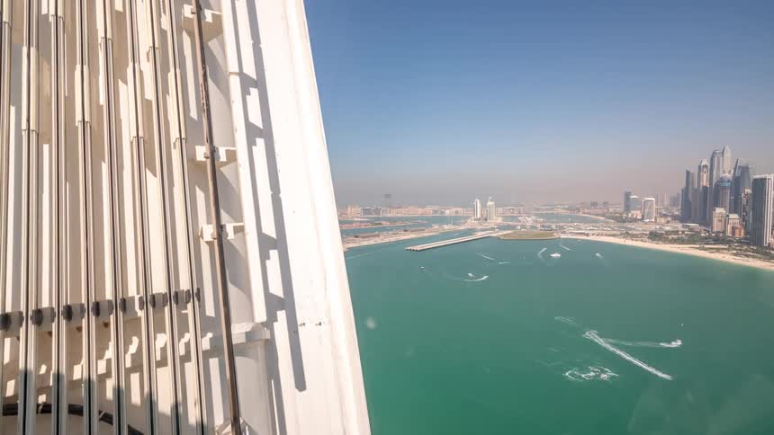 Futuristic streetcars travel in the city of dubai as boats sail in the water and the city skyline is in the distance